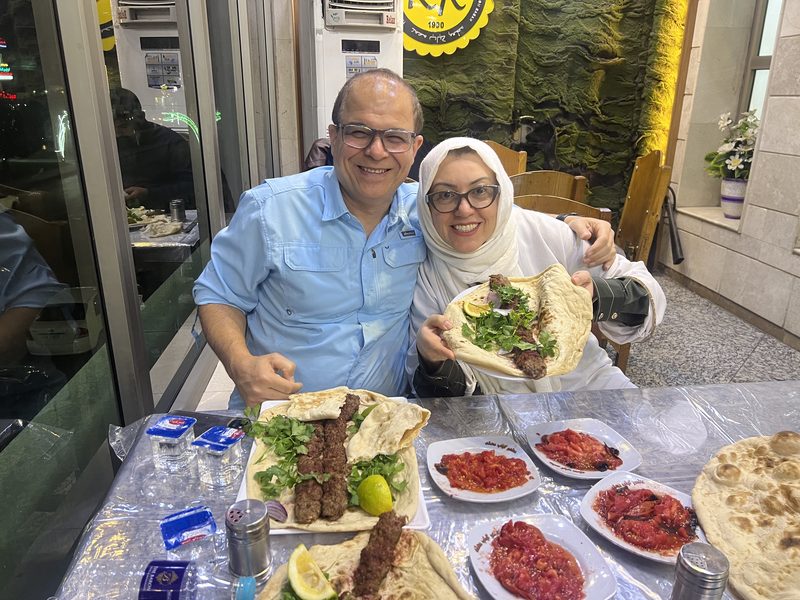 Two happy tourists enjoying a traditional Iraqi barbecue dinner with flatbread and mezze dishes at a local restaurant in Iraq