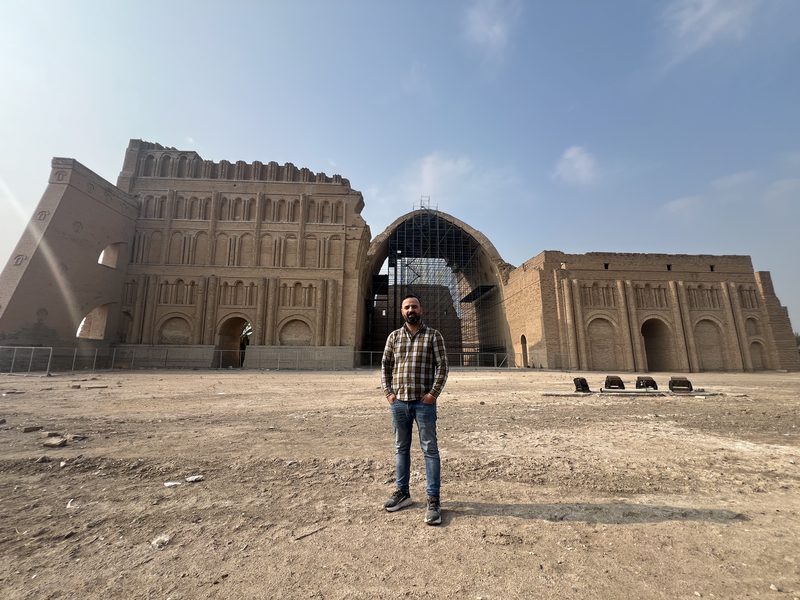 Ali Babylon tour guide standing in front of the ancient Arch of Ctesiphon, a Sassanid-era monument near Baghdad, Iraq