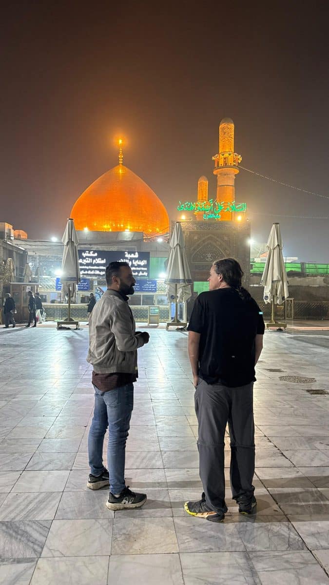 Ali guiding a guest near the golden dome of Imam Hussein Shrine in Karbala at night