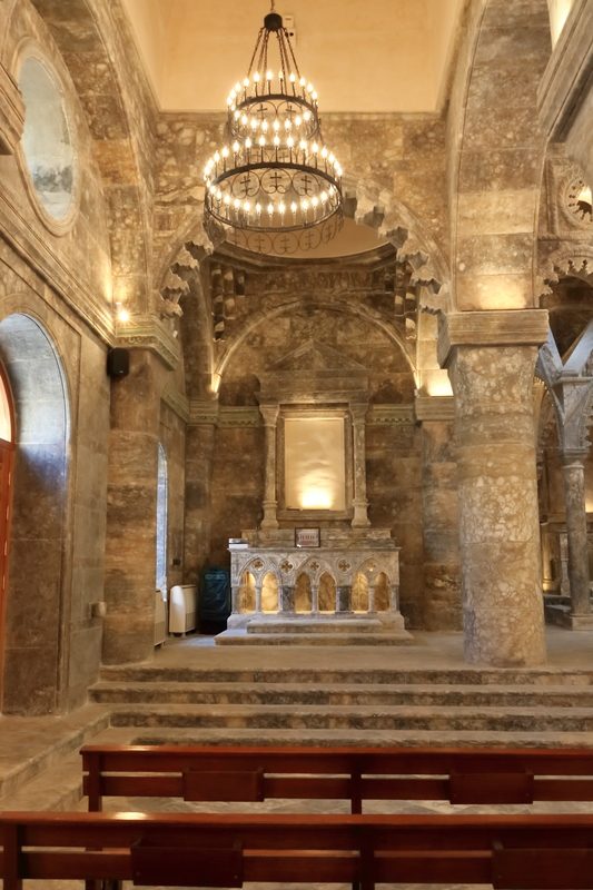 Interior of an ancient Christian church with stone altar and chandelier in Mosul