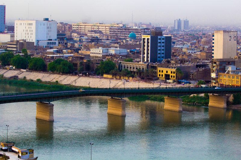 Bridge spanning the Tigris River with Baghdad city skyline at dusk, Iraq