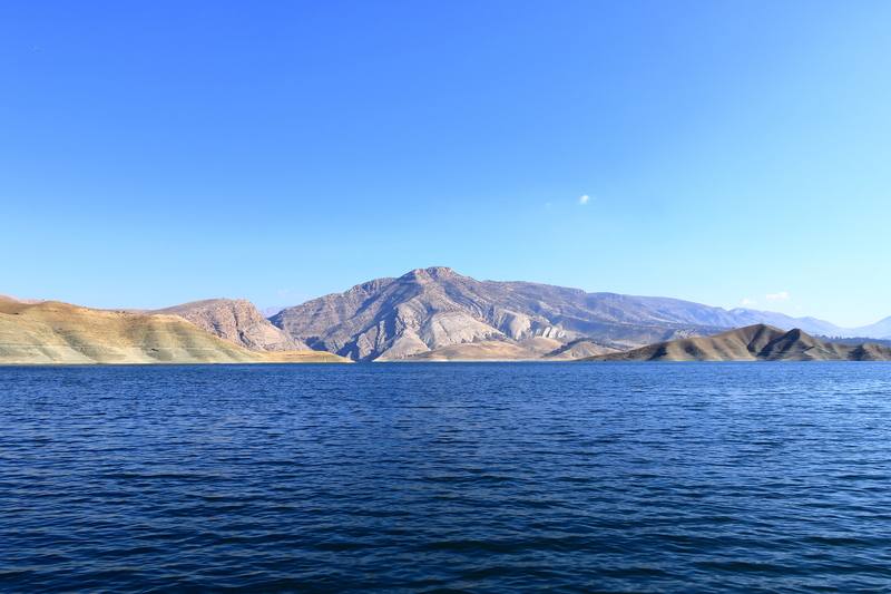 Calm blue waters of Dokan Lake with rocky mountains, Kurdistan Iraq