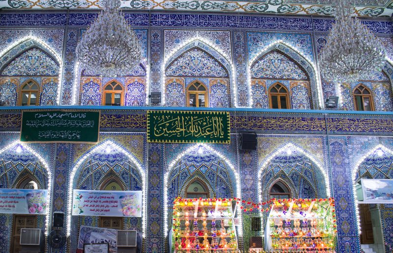 Ornate interior of the Imam Hussein shrine with blue tiled arches and chandeliers in Karbala, Iraq