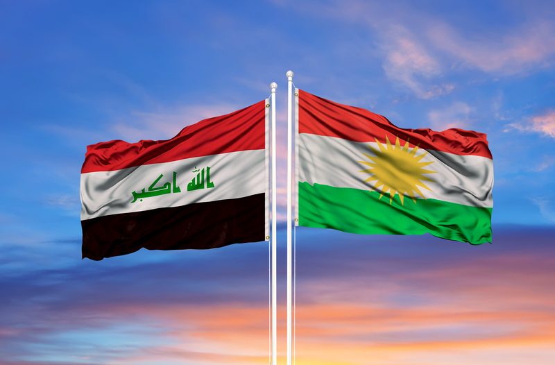 Iraqi national flag and Kurdistan regional flag waving side by side at sunset