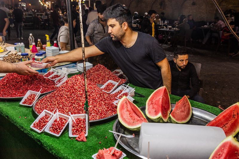 Iraqi street vendor selling pomegranate seeds and watermelon slices at a night market