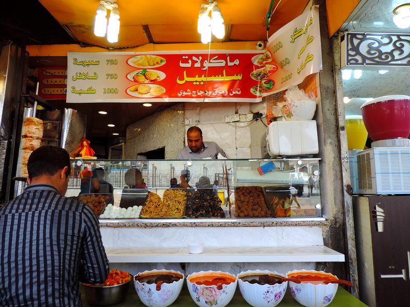 Iraqi street food stall serving falafel, samosa and kubba with bowls of sauce, Iraq