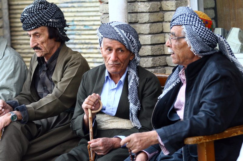 Three Kurdish elderly men wearing traditional headwear sitting together in Kurdistan, Iraq