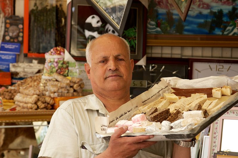 Kurdish vendor presenting a tray of traditional sweets at a market in Kurdistan, Iraq