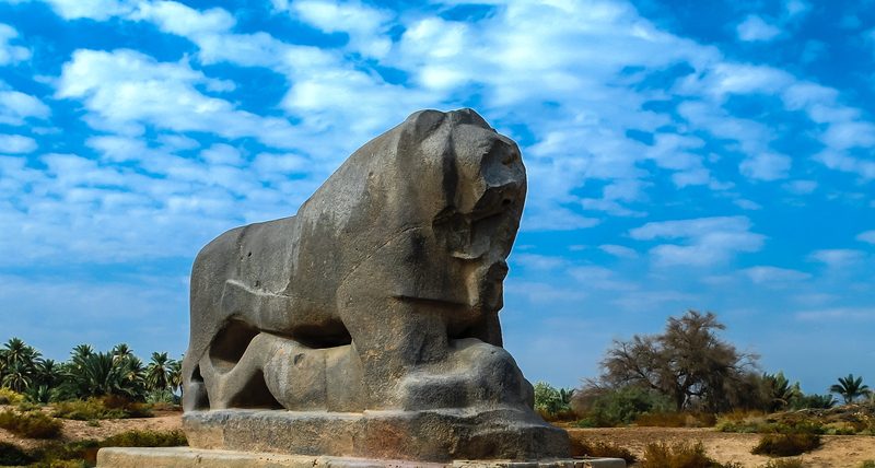The ancient Lion of Babylon stone statue standing against a blue sky at the Babylon ruins, Iraq