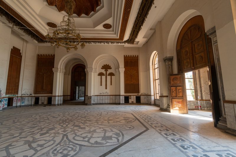 Ornate reception room with arched doorways, chandelier and decorative tiled floor inside Saddam Hussein's palace