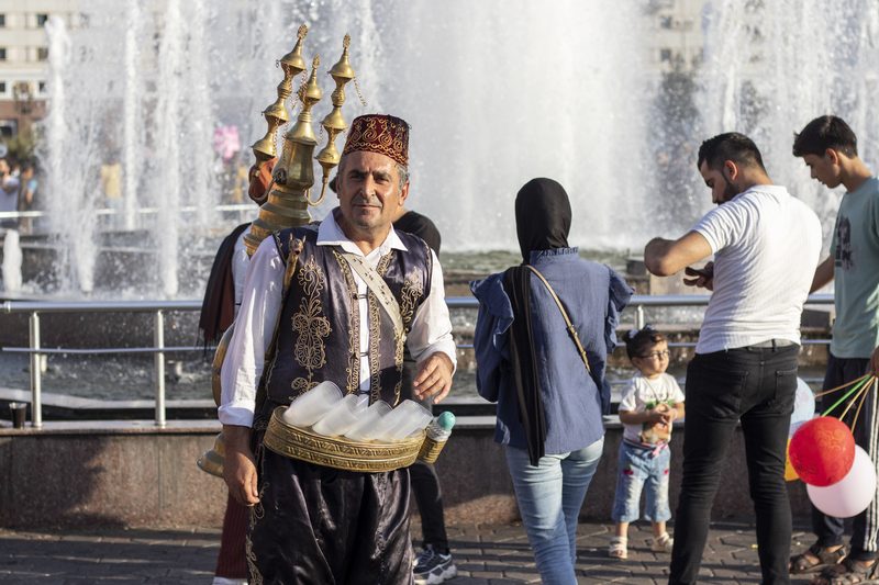Traditional Iraqi tea seller in ornate costume carrying brass tea urns in Erbil, Iraq